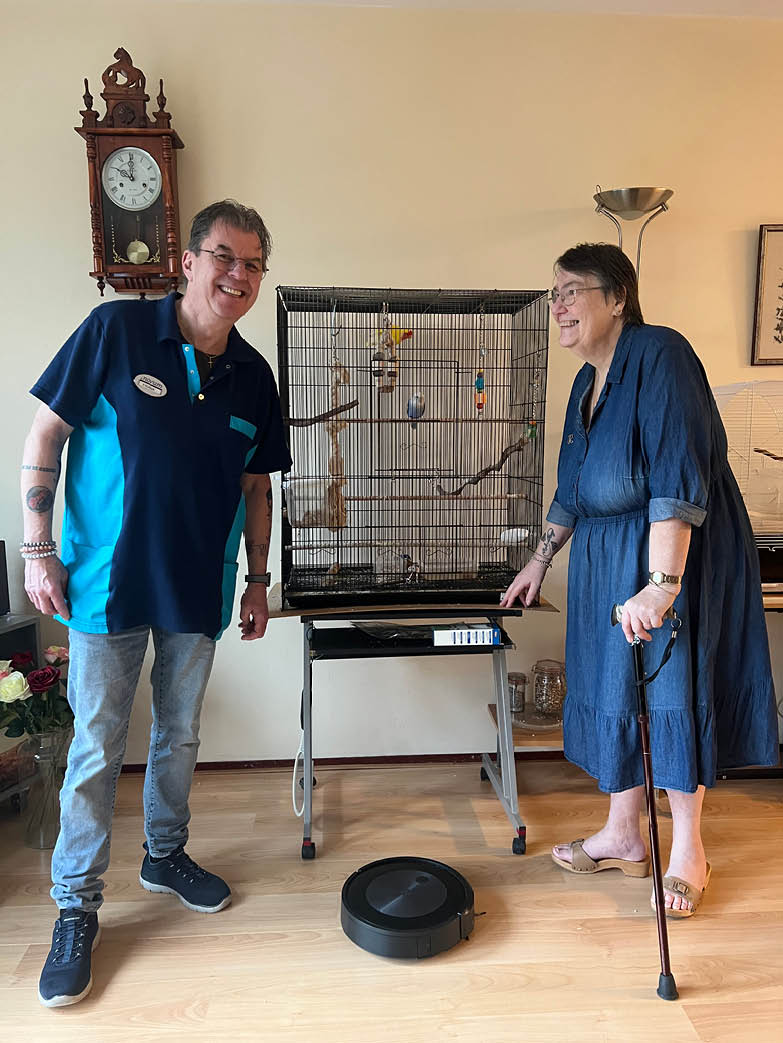 A man and woman are standing in a room with a bird cage. The woman is holding a cane. AI generated content