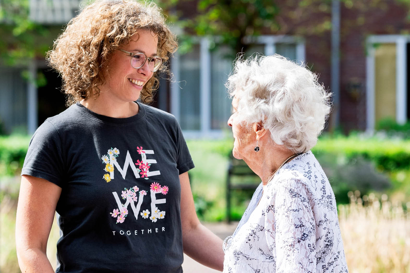 Two women are standing together, one of them wearing a black shirt with white flowers. AI generated content